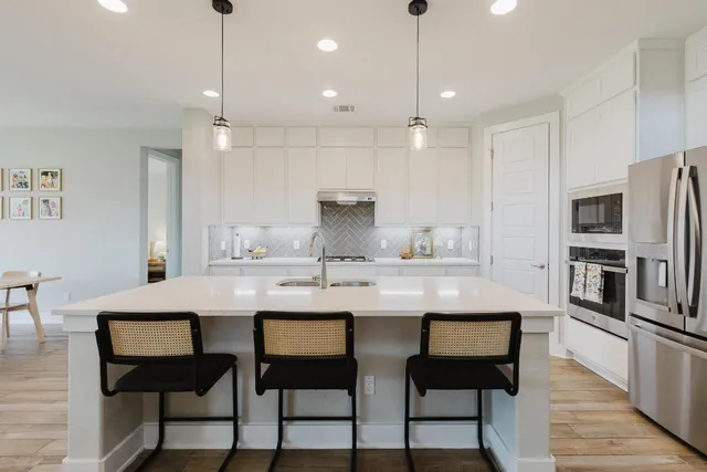 a kitchen with stainless steel appliances granite countertop a kitchen island a stove a table and chairs