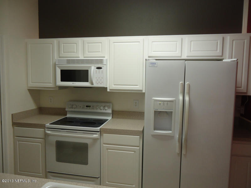 7990 Baymeadows Road East, Unit 1023 Jacksonville, FL 32256 - Photo 8 of 39 a kitchen with white cabinets and white appliances
