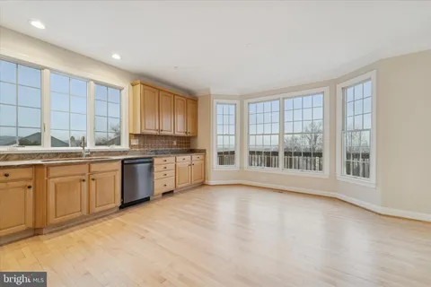 a large kitchen with stainless steel appliances granite countertop a stove a sink dishwasher and a large window with wooden floor