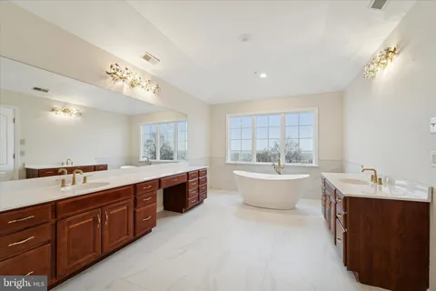 a large spacious bathroom with a double vanity sink a large mirror and a bathtub