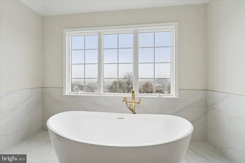 a white bath tub sitting in a bathroom next to a window