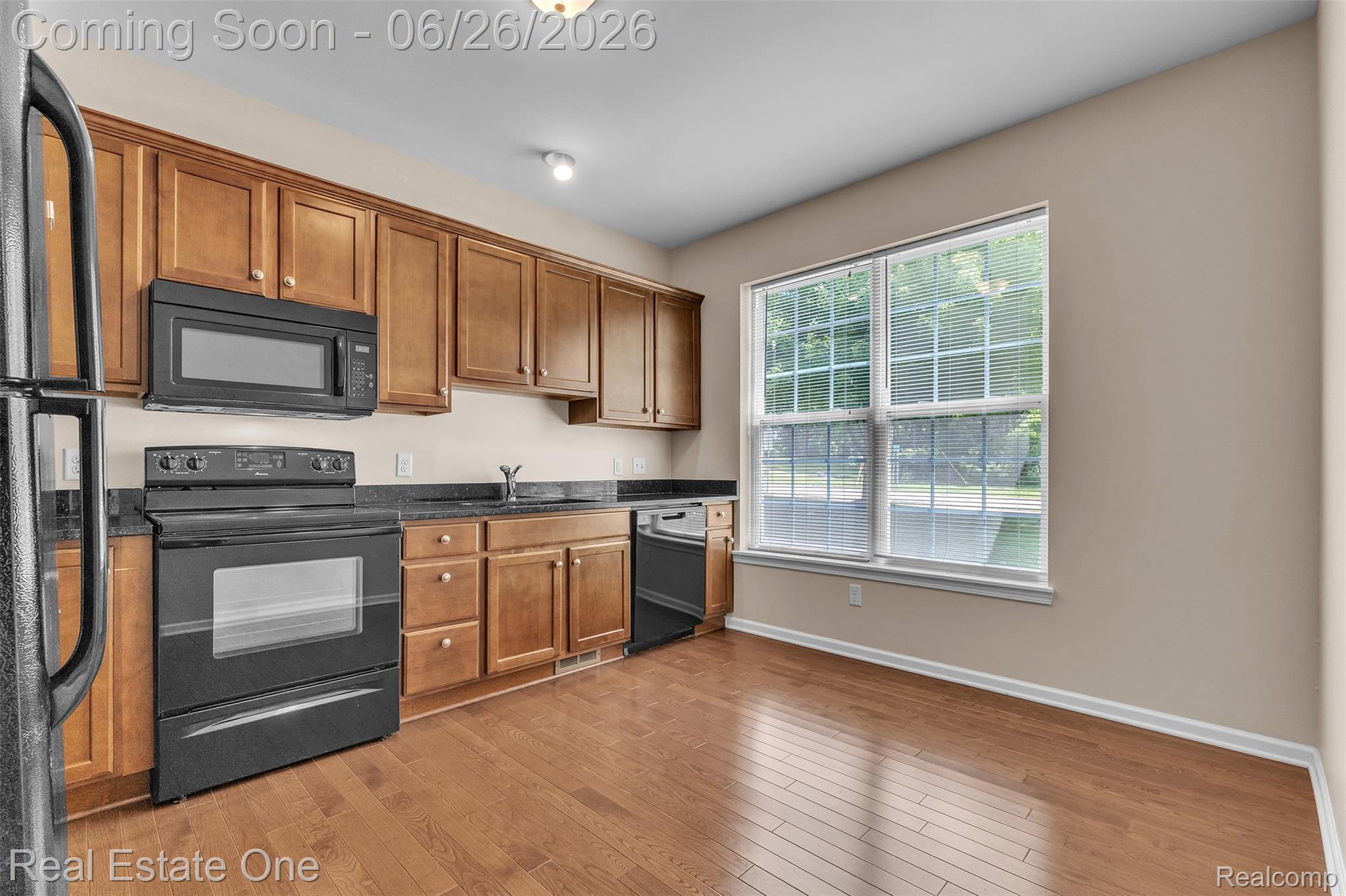 41590 Mitchell Road Novi, MI 48377 - Photo 14 of 45 Kitchen featuring wood-finish flooring, full-height cabinetry with gold-tone hardware, granite-style countertops, and a black appliance suite