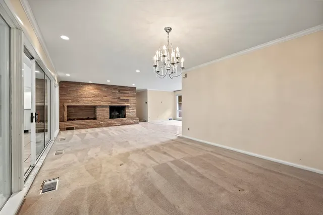 en empty room with a fireplace and chandelier