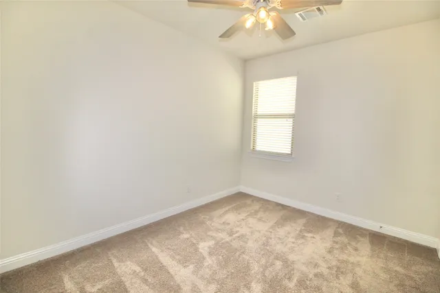 an empty room with a chandelier fan and windows