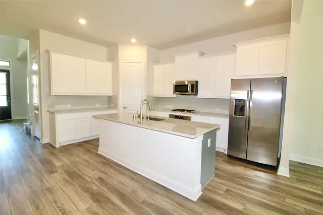 a kitchen with stainless steel appliances a refrigerator sink and white cabinets