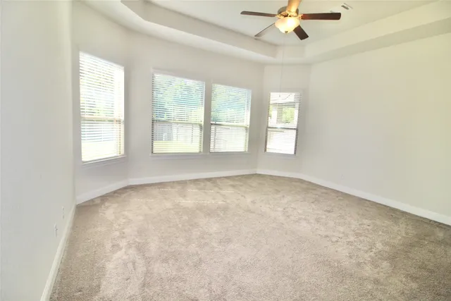 an empty room with chandelier fan and windows