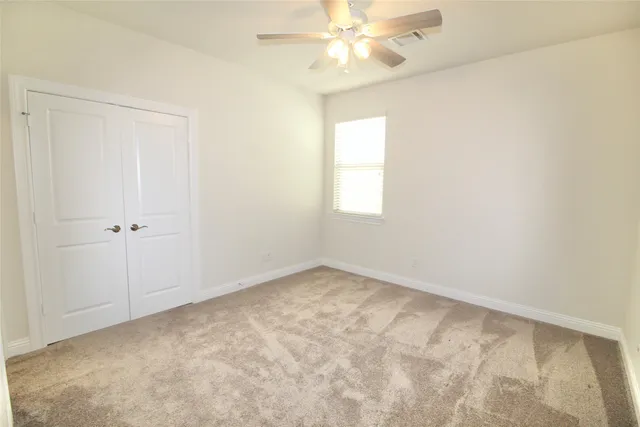 an empty room with a window and a fan