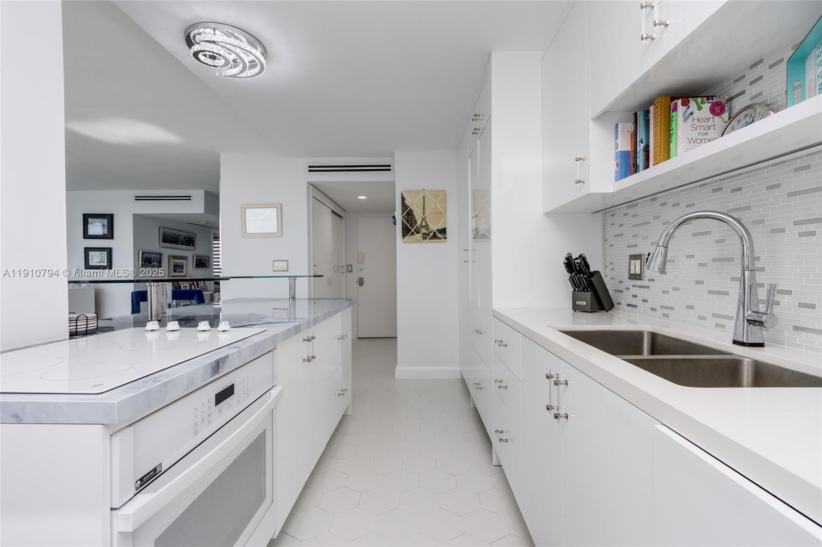 1200 South Ocean Boulevard, Unit 9F Boca Raton, FL 33432 - Photo 5 of 55 a large white kitchen with a sink and a stove with wooden floor