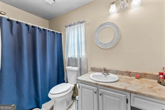 a bathroom with a sink a toilet mirror vanity and a shower
