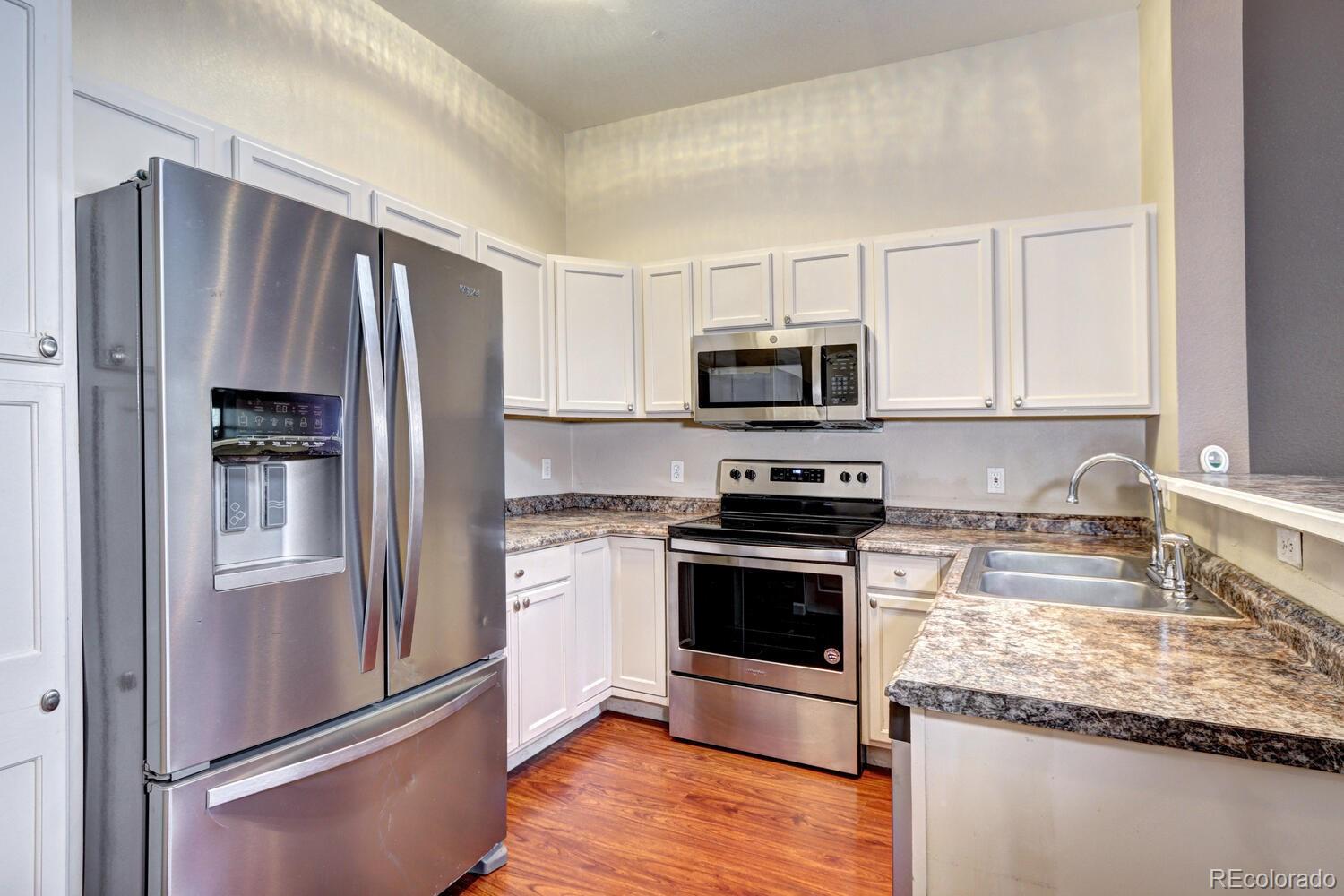 8707 East Florida Avenue, Unit 304 Denver, CO 80247 - Photo 13 of 26 a kitchen with granite countertop a refrigerator stove and microwave