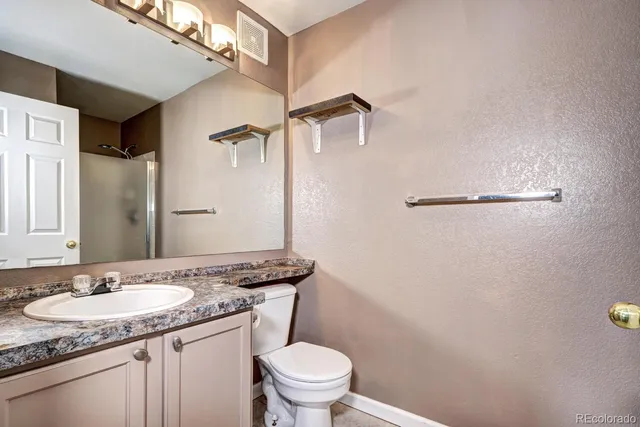 a bathroom with a granite countertop sink toilet and a mirror