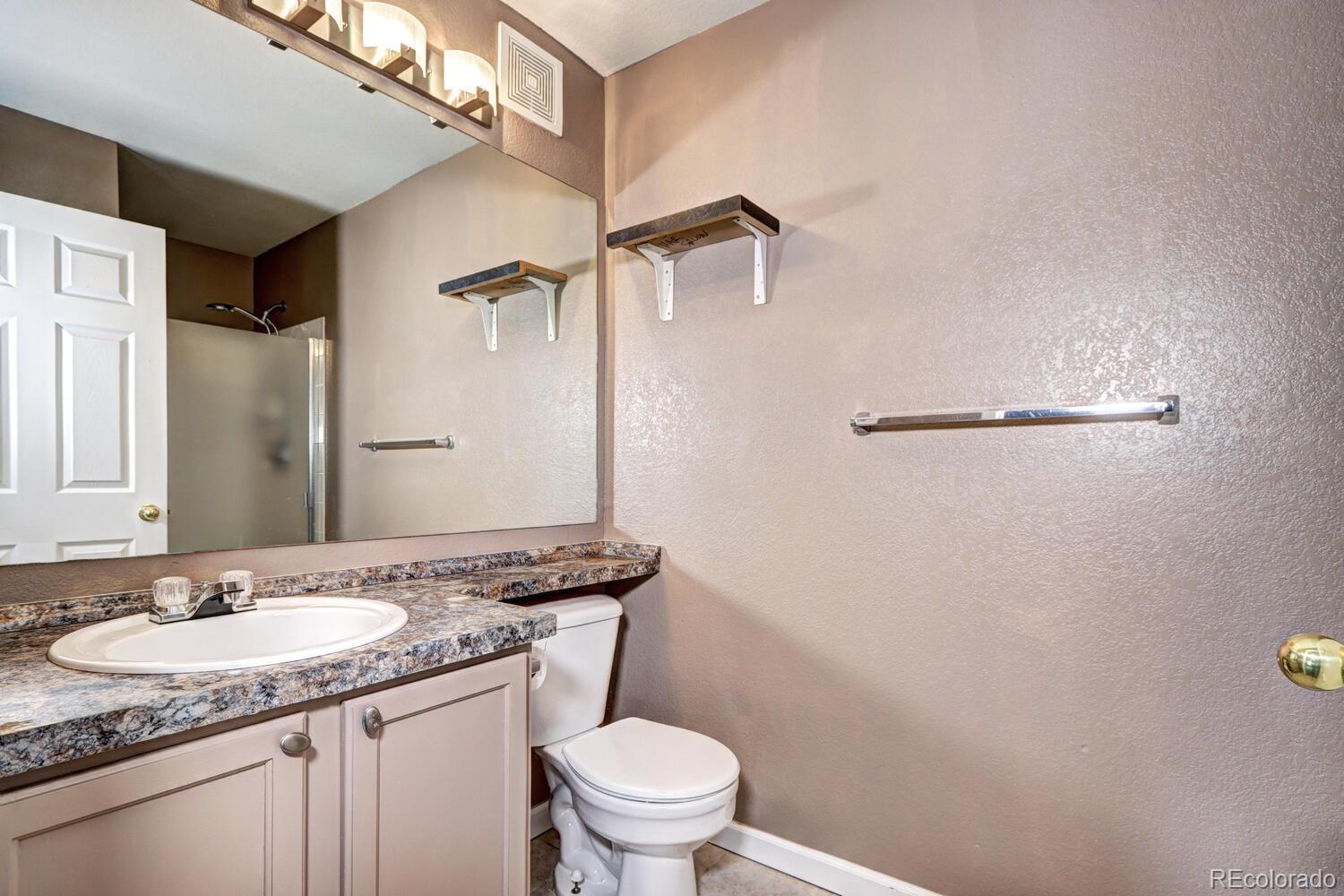 8707 East Florida Avenue, Unit 304 Denver, CO 80247 - Photo 23 of 26 a bathroom with a granite countertop sink toilet and a mirror