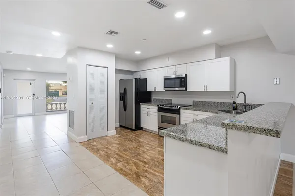 a kitchen with stainless steel appliances granite countertop a refrigerator and a sink