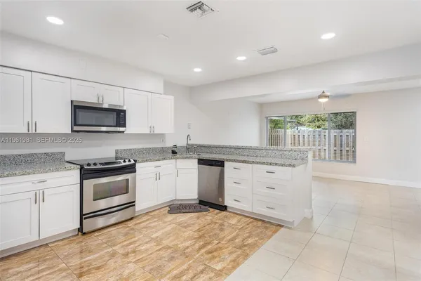 a kitchen with granite countertop white cabinets and appliances