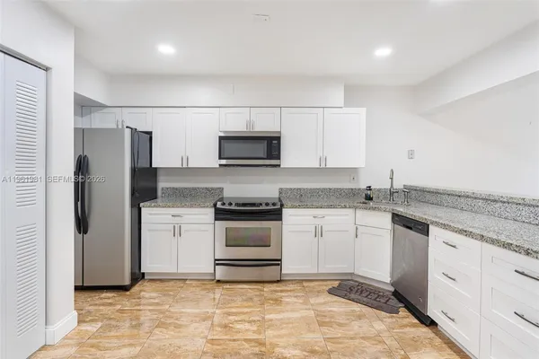a kitchen with granite countertop a sink and stainless steel appliances