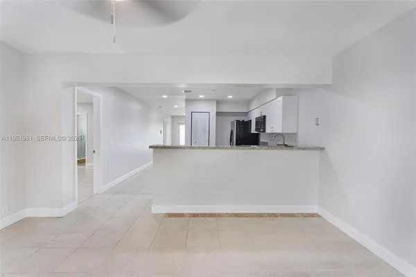 a view of kitchen with kitchen island white cabinets and refrigerator