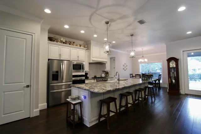 a kitchen with stainless steel appliances granite countertop a refrigerator a stove a sink a dining table and chairs with wooden floor