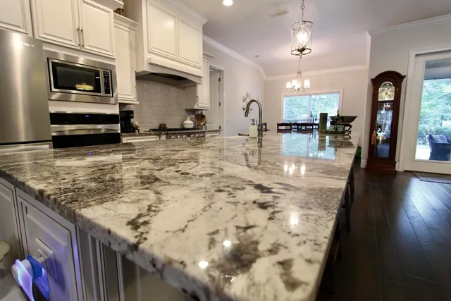 a view of a kitchen with kitchen island a sink stainless steel appliances wooden floor and a view of living room