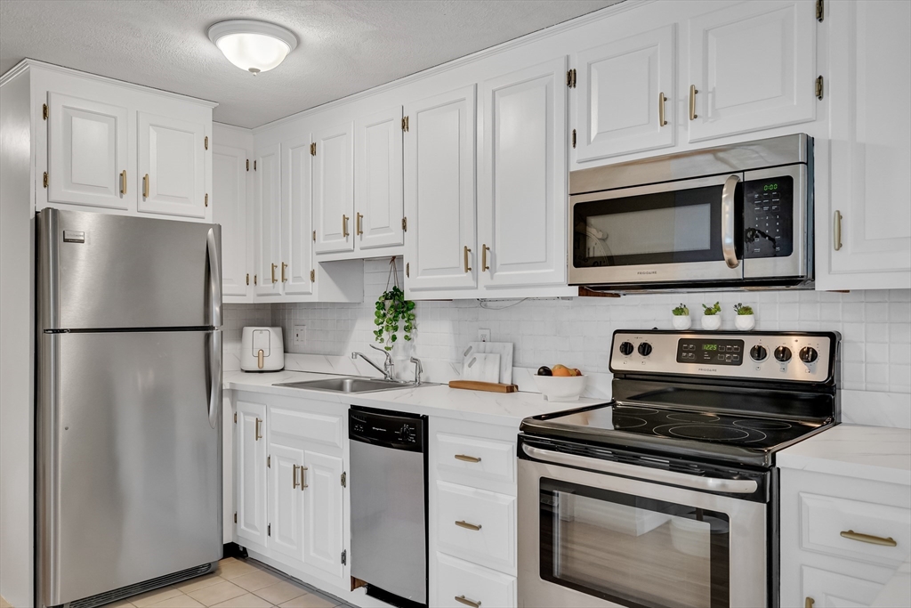 71 Stone Street, Unit 5 Walpole, MA 02081 - Photo 3 of 18 a kitchen with cabinets stainless steel appliances and a wooden floor