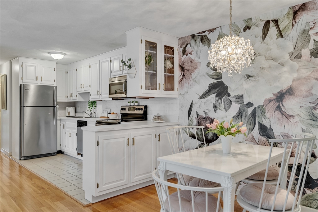 71 Stone Street, Unit 5 Walpole, MA 02081 - Photo 5 of 18 a kitchen with stainless steel appliances granite countertop a refrigerator a sink dishwasher a stove and white cabinets with wooden floor