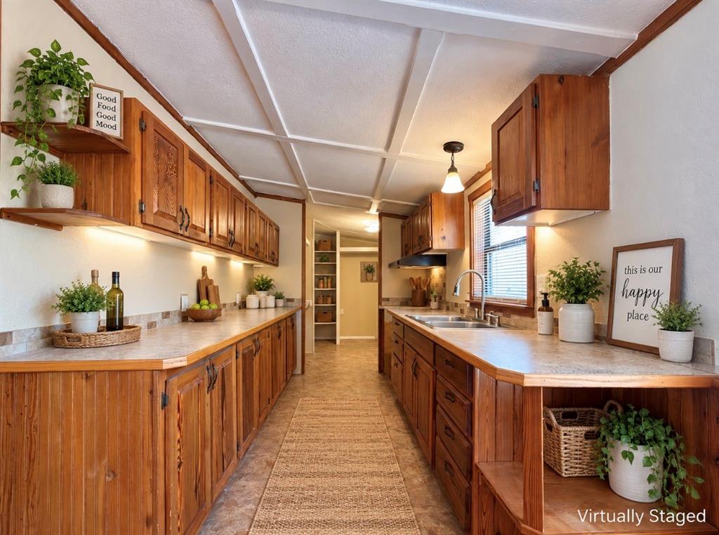 4676 Old Dallas Road Elm Mott, TX 76640 - Photo 7 of 21 Galley-style kitchen featuring wood-finish cabinetry, ample countertop space, undermount sink, and integrated overhead lighting