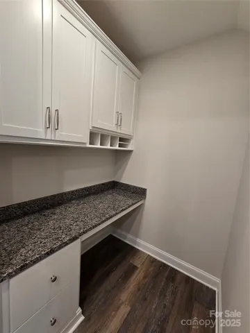 a kitchen with granite countertop white cabinets and a wooden floor