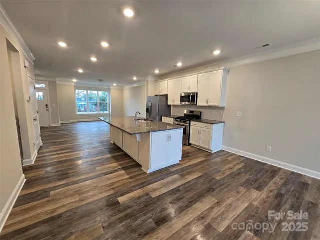 a large kitchen with stainless steel appliances a large counter top a stove and a refrigerator