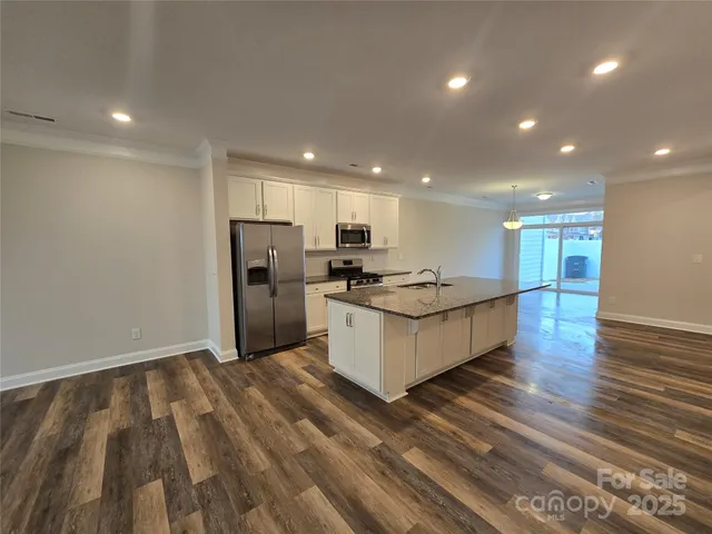 a large kitchen with stainless steel appliances a large counter top and wooden floors