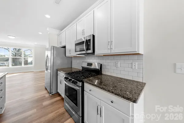 a kitchen with stainless steel appliances granite countertop a stove a sink and a refrigerator