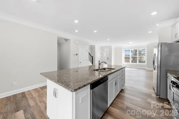 a kitchen with stainless steel appliances granite countertop a sink and a refrigerator