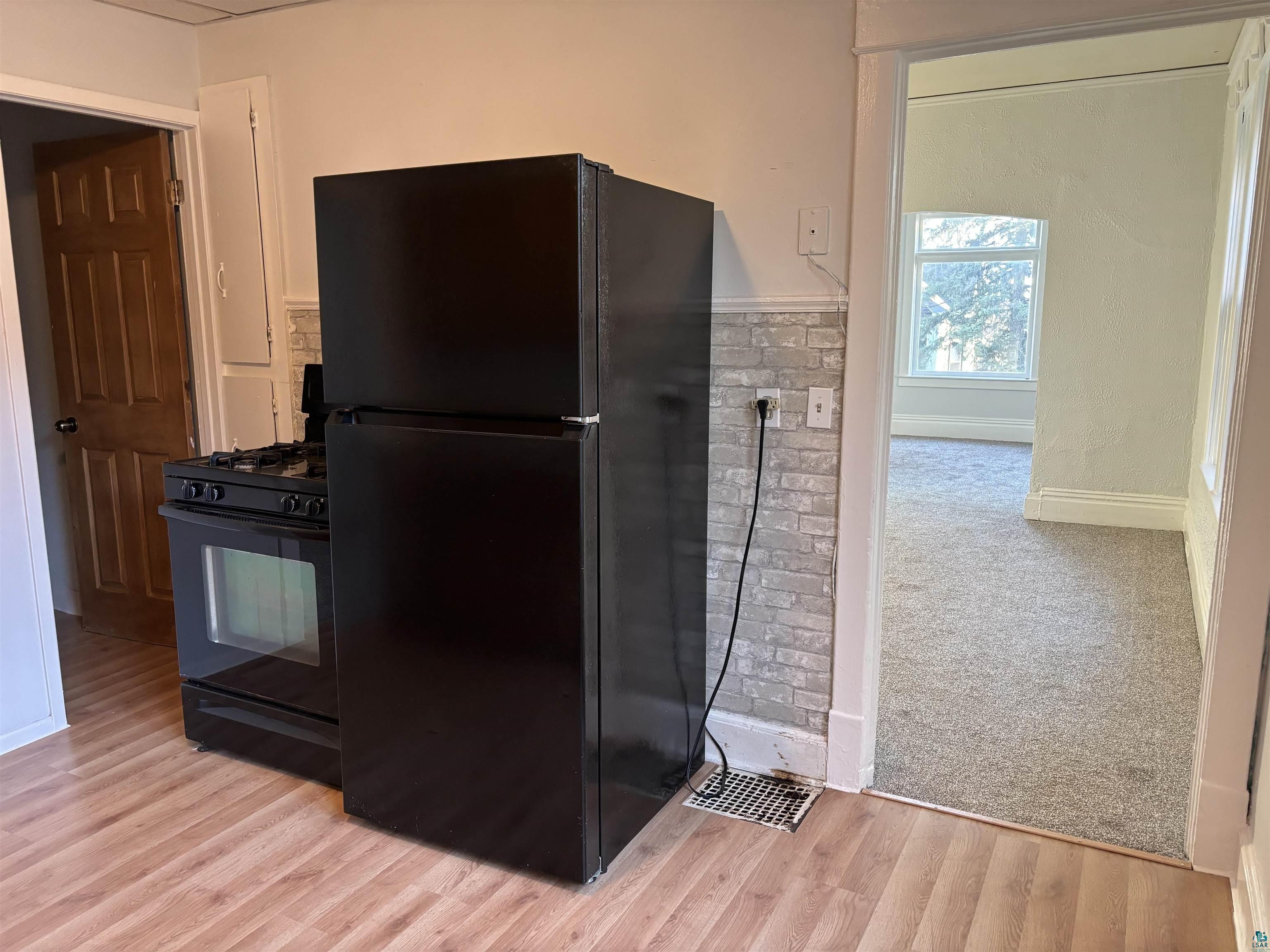 Kitchen featuring light wood-type flooring and black appliances