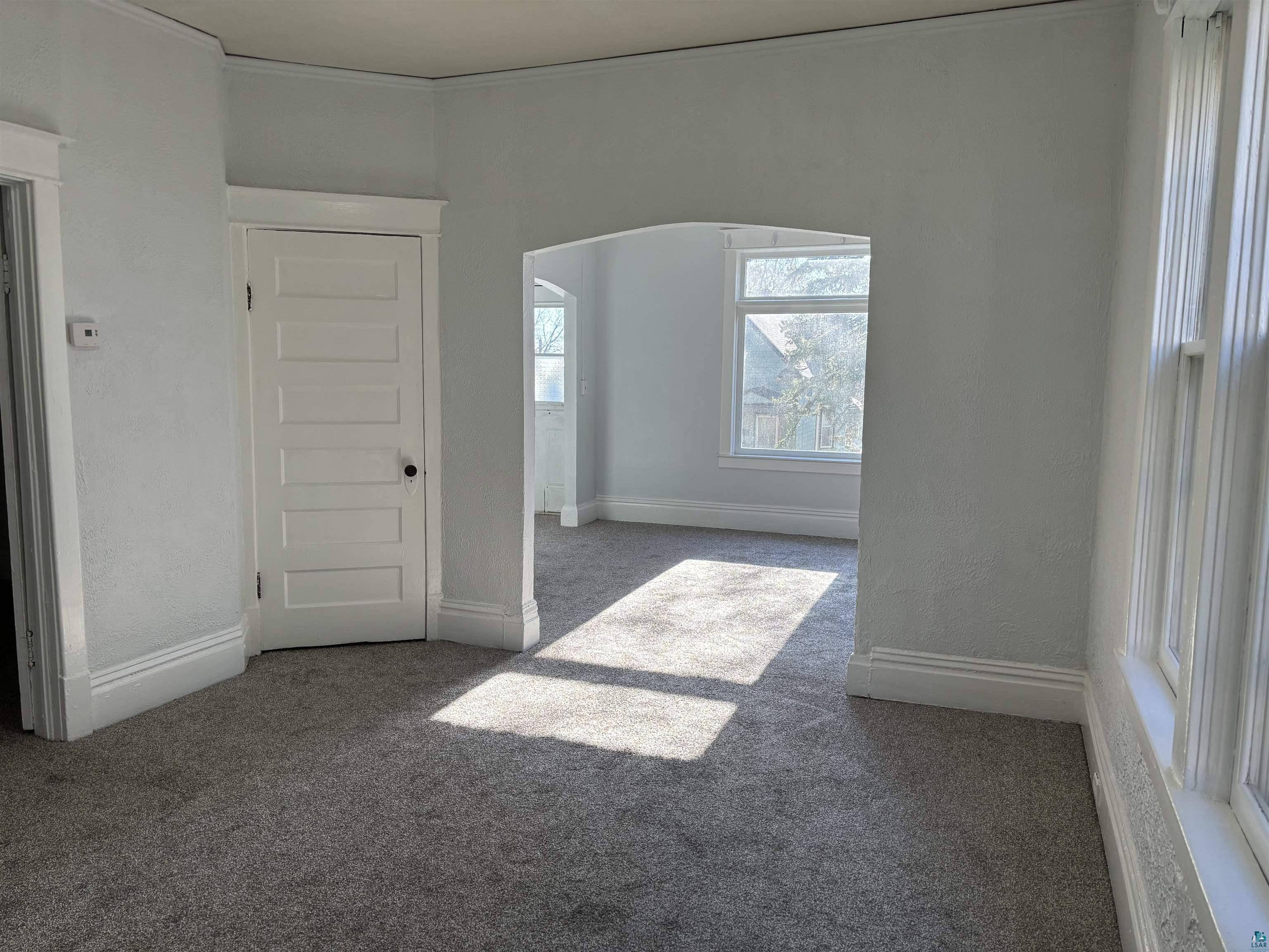 Spare room with dark colored carpet and crown molding