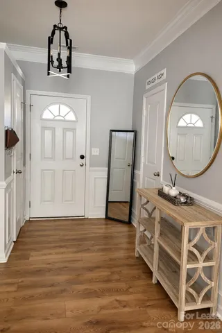 a view of a hallway with wooden floor cabinet and a chandelier