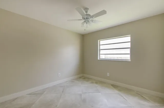 an empty room with a window and a fan
