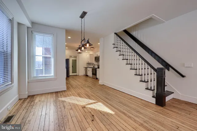 a view of an empty room with window wooden floor and a kitchen