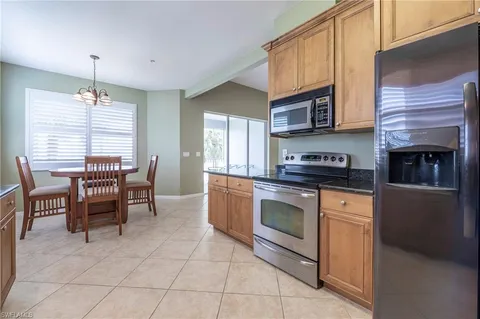a kitchen with stainless steel appliances granite countertop a stove top oven a sink a dining table and chairs
