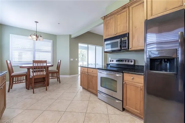 a kitchen with stainless steel appliances granite countertop a stove top oven a sink a dining table and chairs