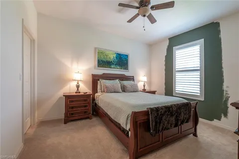 a bed sitting in a bedroom next to a window and a chandelier