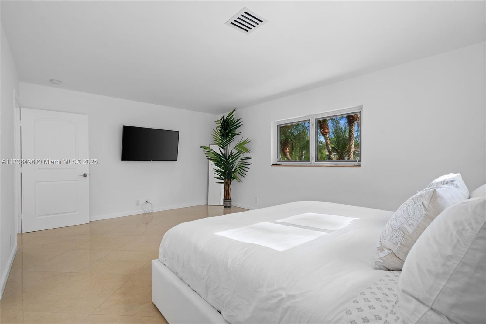 1144 Adams Street Hollywood, FL 33019 - Photo 17 of 51 a bedroom with a large bed a flat tv screen and a potted plant