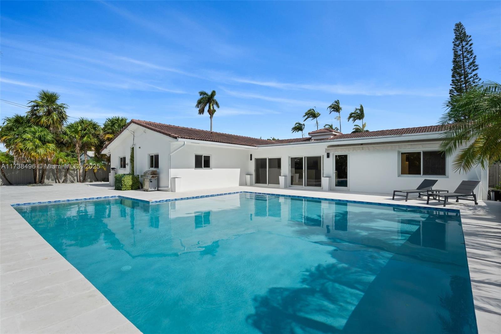 1144 Adams Street Hollywood, FL 33019 - Photo 45 of 51 a white house with a large pool yard and couches chairs