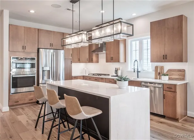 a kitchen with kitchen island granite countertop a sink cabinets stainless steel appliances and a counter top space