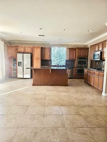 a living room with stainless steel appliances kitchen island granite countertop a large window and a couch