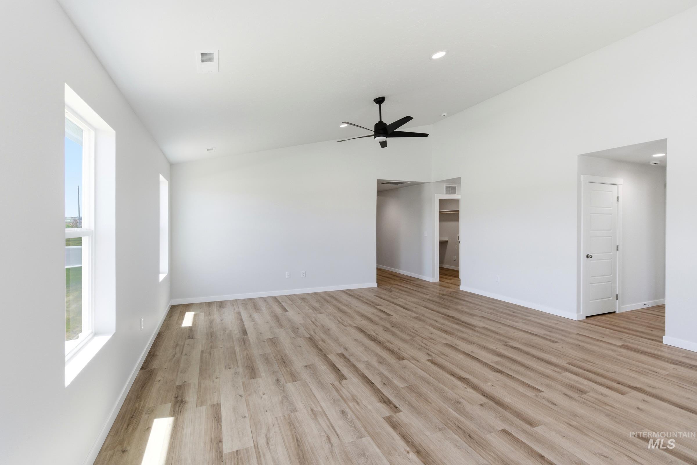 8317 South Tyrion Way Kuna, ID 83634 - Photo 7 of 22 Spacious room featuring wood-finish flooring, vaulted ceilings, a contemporary black ceiling fan, and multiple windows