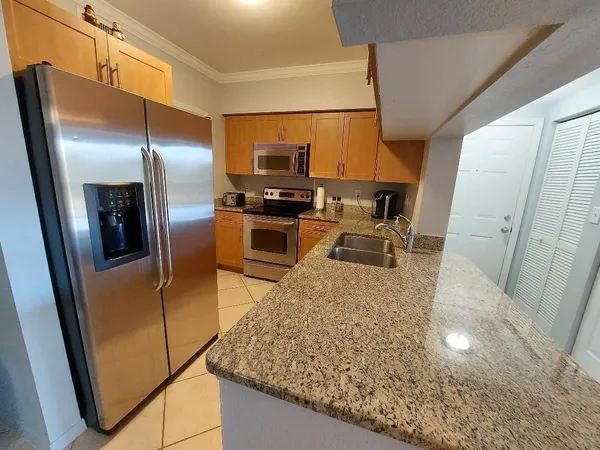 a kitchen with stainless steel appliances granite countertop sink stove refrigerator and microwave
