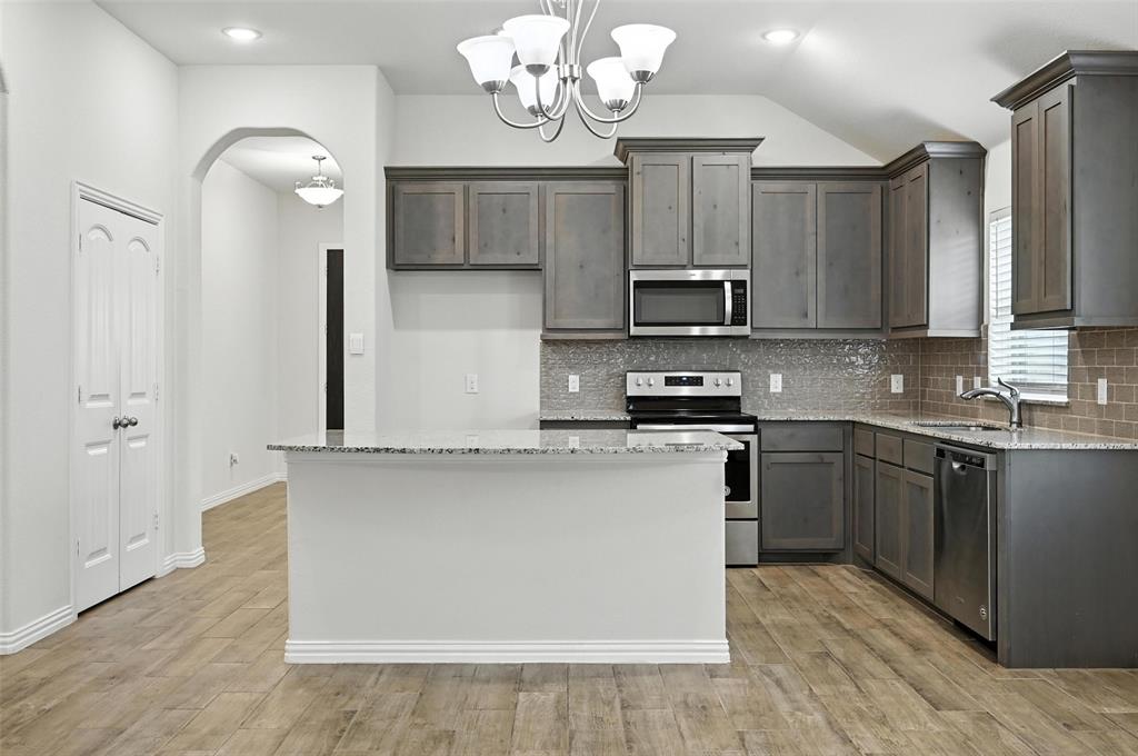 5 Pheasant Run Sanger, TX 76266 - Photo 8 of 27 Kitchen with light stone counters, appliances with stainless steel finishes, tasteful backsplash, a center island, and decorative light fixtures