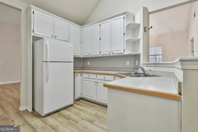 a kitchen with a sink a refrigerator a window and white cabinets