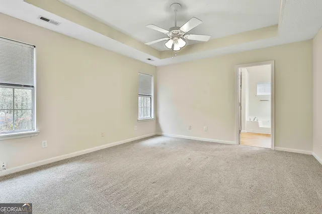 an empty room with windows and fan