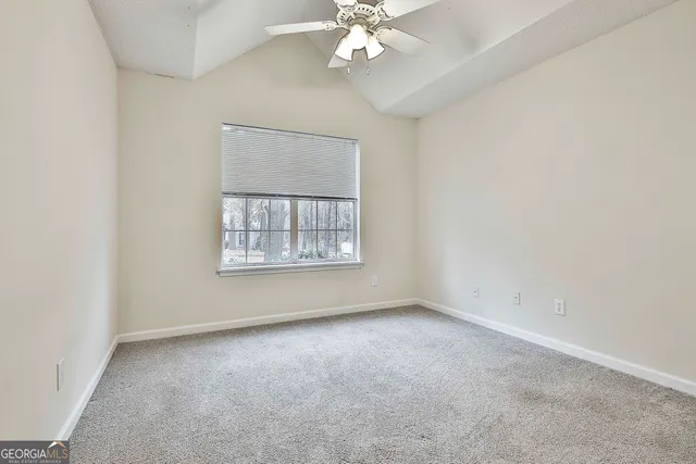 an empty room with a chandelier fan and windows