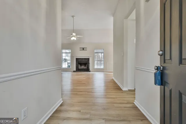 a view of an empty room with wooden floor fireplace and a window