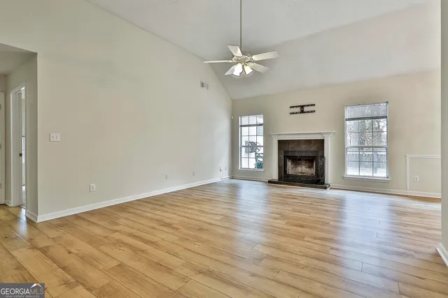 an empty room with wooden floor fireplace and windows